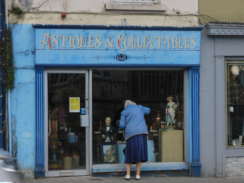 Woman peering in the window of an antique store in Kilkenny, Ireland - one of my favorite spots for a day trip from Dublin!